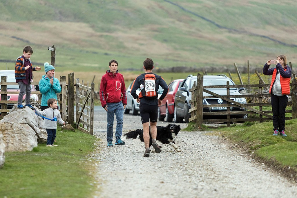 Chris Perry receives encouragement from three-times Fellsman winner Adam, along with Chris's family and a four-legged supporter. Photo: Bob Smith/grough