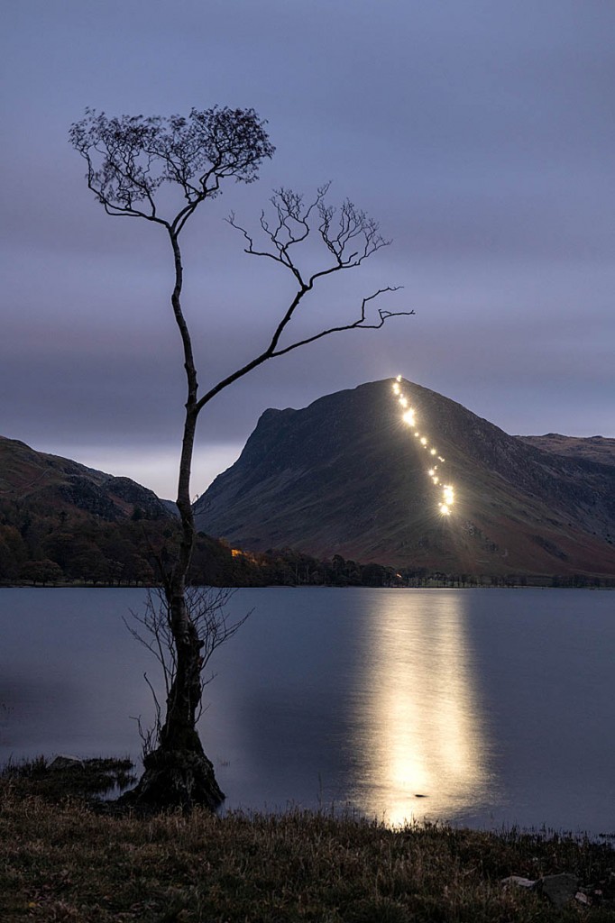 The lights of walkers' torches are reflected in Buttermere. Photo: Carmen Norman Photography