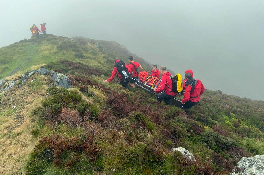 Rescuers stretcher the injured runner from the fell. Photo: Keswick MRT