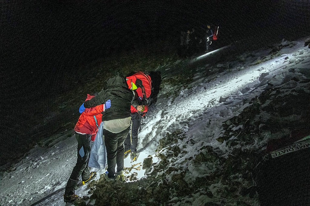 Rescuers support one of the group across the slope. Photo: Keswick MRT