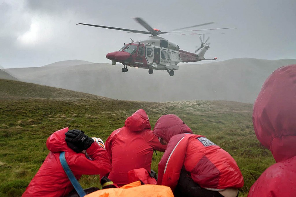 Rescuers with the Coastguard helicopter at the scene. Photo: Keswick MRT Rescuers with the Coastguard helicopter on the mountain. Photo: Keswick MRT