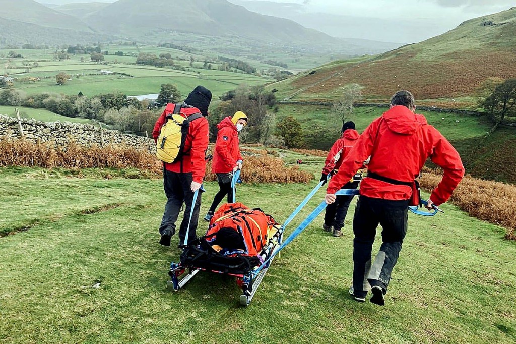 Rescuers stretcher the walker from the fell. Photo: Keswick MRT