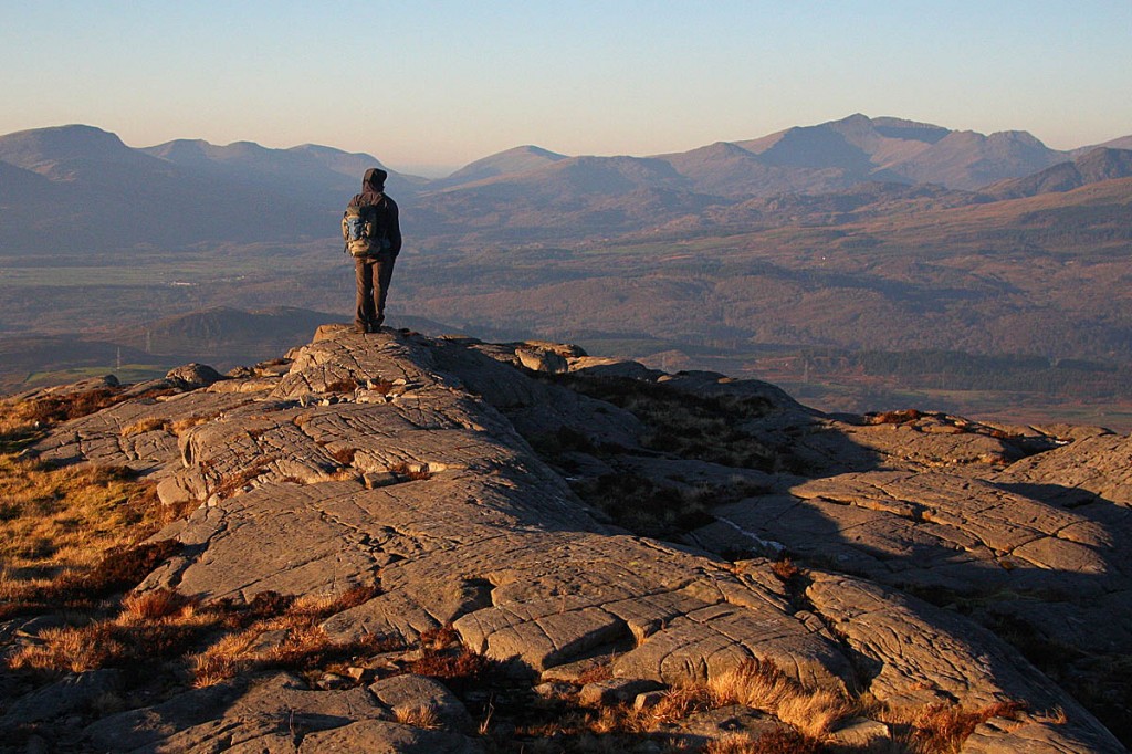 Aled Williams stands at the summit of Foel Penolau, looking to Snowdon in the distance. Photo: Myrddyn Phillips