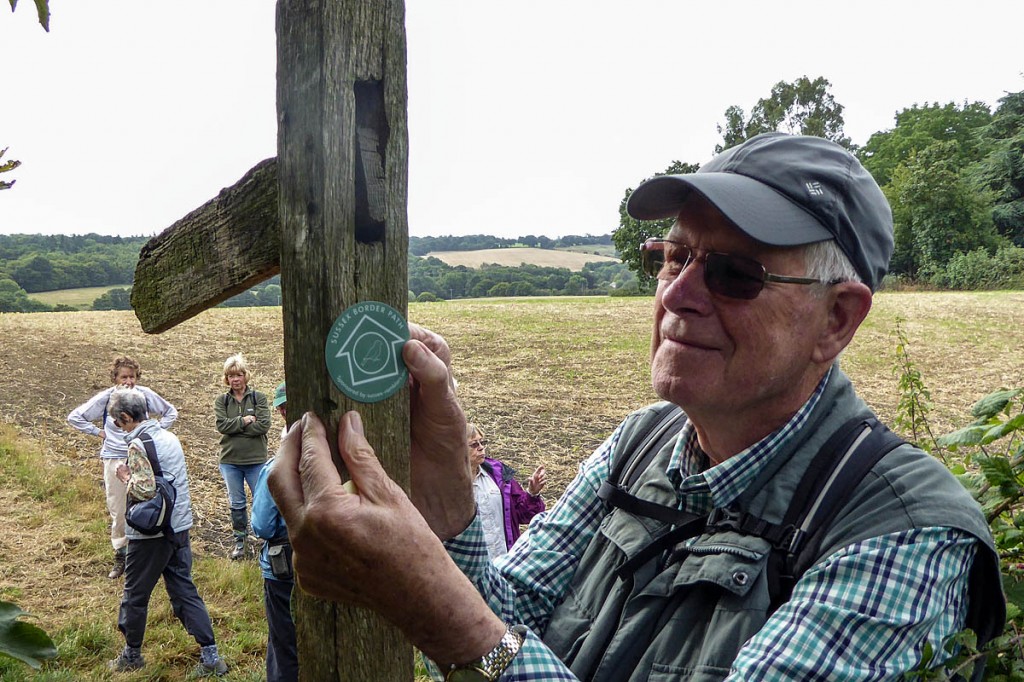 Ramblers volunteer Jerry Kind fixes a label to a roadside finger post on the Sussex Border Path Ramblers volunteer Jerry Kind fixes a label to a roadside finger post on the Sussex Border Path