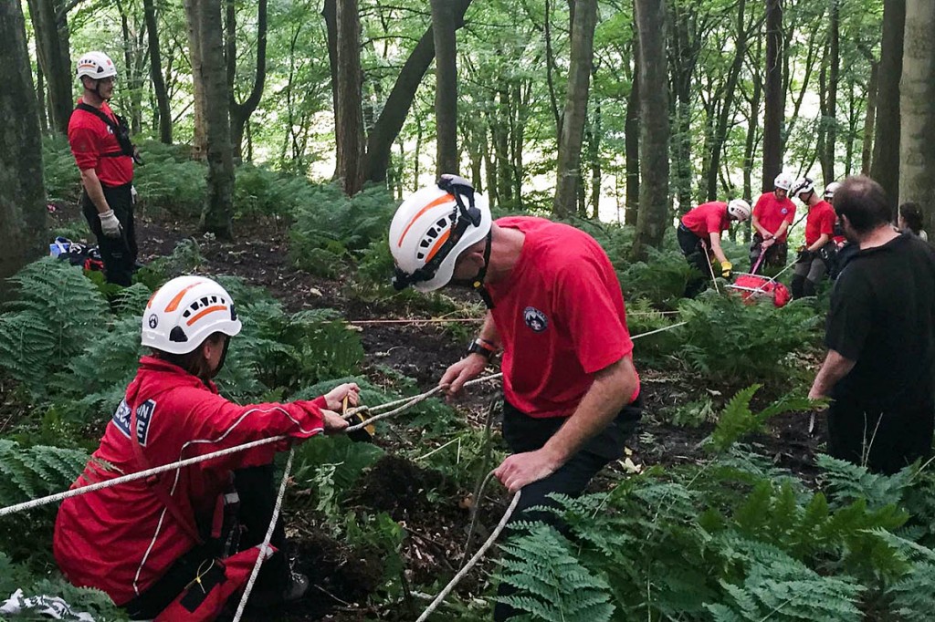 Team members lower the woman in a stretcher, using a rope system. Photo: Calder Valley SRT