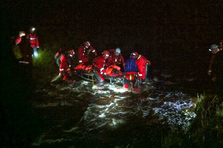 Rescuers carry the stretcher across the river