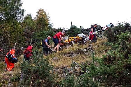 The collapsed man is stretchered up the hillside to the helicopter. Photo: GNAAS The collapsed man is stretchered up the hillside to the helicopter. Photo: GNAAS