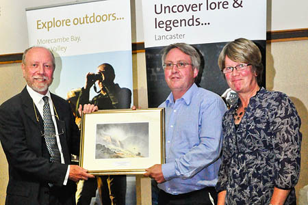 President Roly Smith, left, presents the Williamses with the award, which takes the form of an original painting of Scafell by guild member David Bellamy. Photo: Jon Sparks President Roly Smith, left, presents the Williamses with the award, which takes the form of an original painting of Scafell by guild member David Bellamy. Photo: Jon Sparks